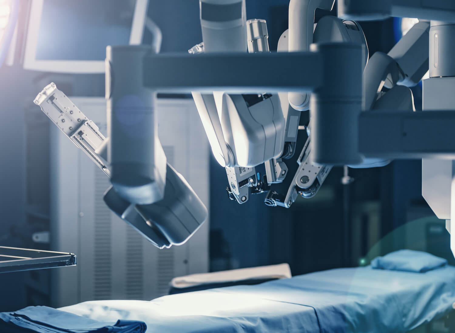 Robotic surgical arms positioned over an empty operating table in a modern, high-tech medical facility.